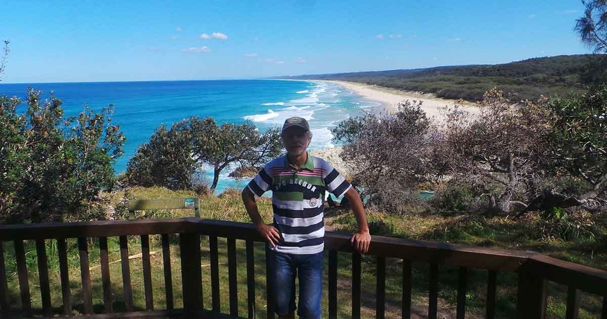 vivir en Australia hombre posando delante de un mirador y detrás una playa